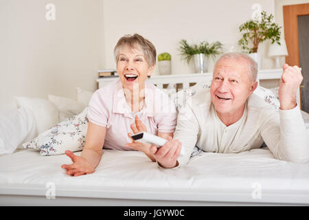 Coppia senior di guardare la TV a letto Foto Stock