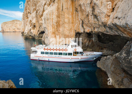 Grotta di Nettuno Sardegna, un tour in barca è ormeggiata in entrata nella Grotta di Nettuno al di sotto di Capo Caccia, vicino ad Alghero, a nord-ovest della Sardegna. Foto Stock