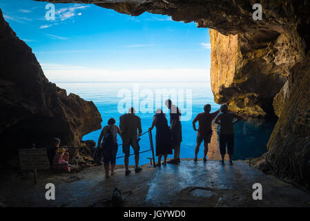 Grotta di Nettuno Sardegna, turisti guardare nel blu brillante acqua di mare all'ingresso della Grotta di Nettuno a Capo Caccia vicino ad Alghero, Sardegna Foto Stock