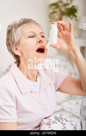 Senior donna con asma mediante inalatore Foto Stock