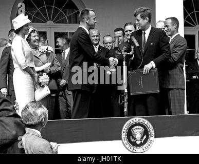 Il presidente John F. Kennedy si congratula con l'astronauta Alan B.Shepard Jr., il primo americano nello spazio, nel suo storico 5 maggio 1961 cavalcata in libertà 7 veicoli spaziali e lo presenta con la NASA Distinguished Service Award. La cerimonia ha avuto luogo sulla Casa Bianca prato. Shepard la moglie Louise (a sinistra in abito bianco e hat), e sua madre erano in presenza così come gli altri sei astronauti Mercury e agenti della NASA, alcuni visibili in background. Foto Stock