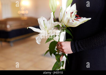 Close up di donna con giglio fiori ai funerali Foto Stock