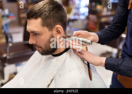 L uomo e il barbiere mani con rifinitore per peli di taglio Foto Stock