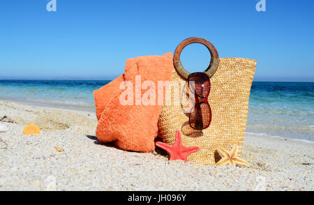 Borsa di paglia e occhiali da sole sulla spiaggia Foto Stock