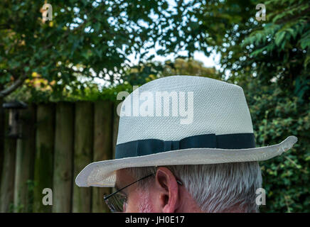 Chiusura del vecchio uomo con i capelli bianchi seduta fuori ingarden indossando un cappello di Panama e la faccia nascosta, London, England, Regno Unito Foto Stock