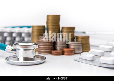 Pila di monete per far crescere il business con strumenti medicali stetoscopio, risparmiando denaro concetto. Foto Stock