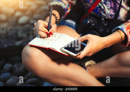 Giornalista reporter con telecamera prende appunti su un notebook. Foto Stock