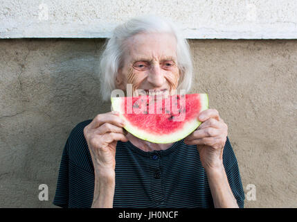 Allegro nonna mangiare anguria frutto nel cortile posteriore Foto Stock