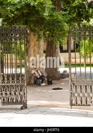 Busker suonare la fisarmonica a piano fuori dai cancelli al royal giardini presso il palazzo reale di Aranjuez nella provincia di Madrid di Spagna Foto Stock