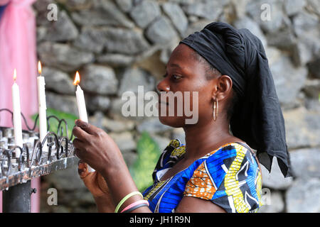 Donna africana accendendo candele in chiesa. Lomé. Il Togo. Foto Stock