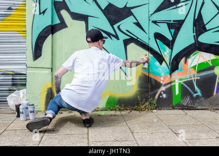 Graffiti artist verniciatura a spruzzo di un muro, Nottingham, Inghilterra, Regno Unito Foto Stock