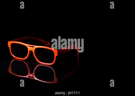 Orange occhiali 3d nero sulla superficie riflettente Foto Stock