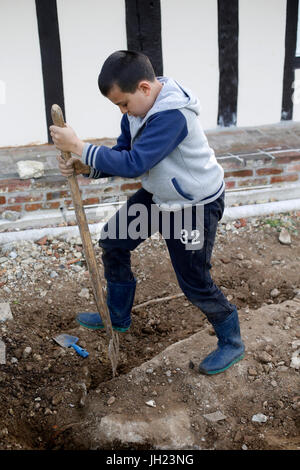 Il 10-anno-vecchio ragazzo utilizzando un rastrello. La Francia. Foto Stock