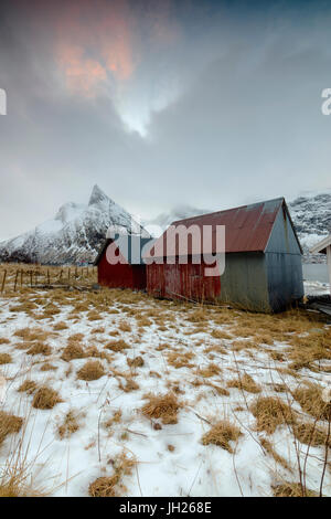 Nuvole sulle cime innevate sopra tipica capanna in legno chiamato Rorbu, Senja, Ersfjord, Troms County, Norvegia, Scandinavia, Europa Foto Stock