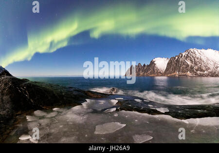 Panorama del mare ghiacciato e picchi rocciosi illuminato dalle luci del nord, Tungeneset, Senja, Troms, Norvegia Foto Stock