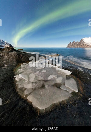 Le luci del nord si accendono i picchi rocciosi e mare ghiacciato nella notte polare, Tungeneset, Senja Troms, Norvegia Foto Stock