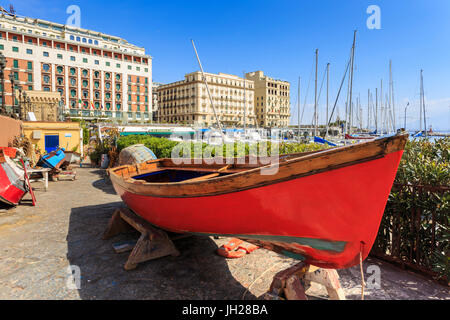 Colorate barche a remi in riparazione presso la marina Borgo Marinaro, con sfondo di Grand Hotel Chiaia, città di Napoli, Italia Foto Stock