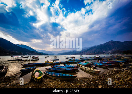 Barche ormeggiate sulle sponde di un lago al tramonto a Pokhara, Nepal, Asia Foto Stock