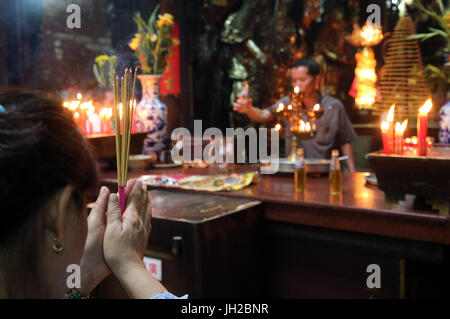 Il tempio taoista. L'imperatore Jade pagoda (Chua Phuoc Hai). Adoratore buddista. La masterizzazione di bastoncini di incenso. Ho Chi Minh City. Il Vietnam. Foto Stock