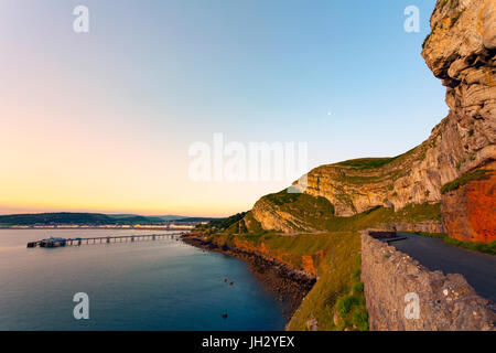 Una spettacolare alba estiva sulla baia a Llandudno con il molo vittoriano e Great Orme formazioni rocciose essendo immerso nella luce del mattino, Llandudno, Wales, Regno Unito Foto Stock