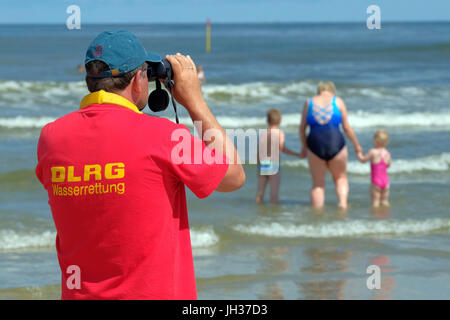 Membri della DLRG vita tedesca il salvataggio della società guarda il nuotatore in onde del mare del Nord sulla spiaggia dell'isola di Spiekeroog, Germania Foto Stock