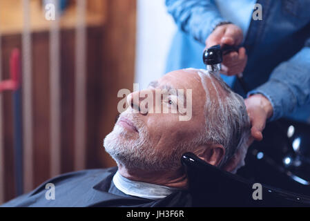 Lieto uomo anziano avente i suoi capelli lavati Foto Stock