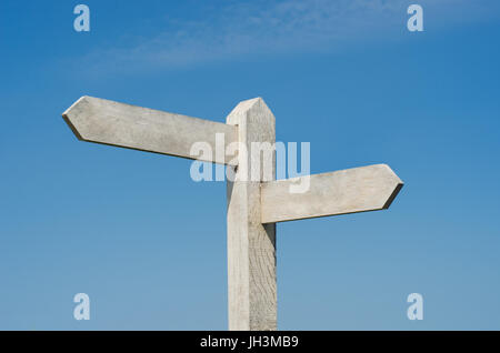 Vecchie indicazioni del cartello in legno con due schede vuote rivolte in direzioni differenti, weathered al bianco brillante contro il cielo blu con luce soffici nuvole. Foto Stock