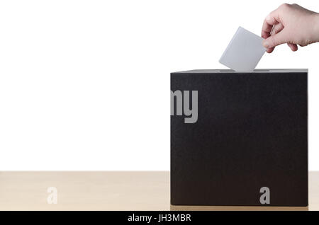 Ponendo mano piegata slittamento voto nella fessura urna luce sul tavolo di legno. Isolato su sfondo bianco. Foto Stock