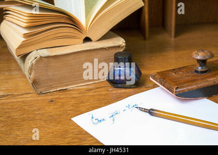 Il testo "una volta" scritto in inchiostro su un foglio di carta e circondato con una vecchia cancelleria. Foto Stock