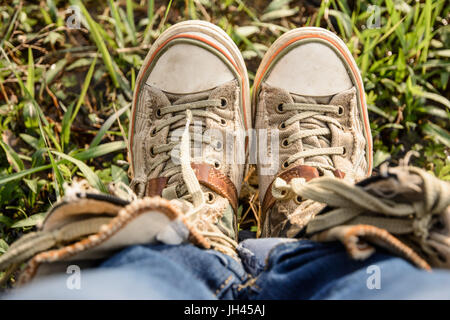 Donna di piedi con shabby sneakers su fotografati da sopra. Foto Stock