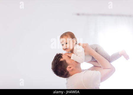 Giovane padre si solleva la sua piccola bambina, all'interno della camera Foto Stock