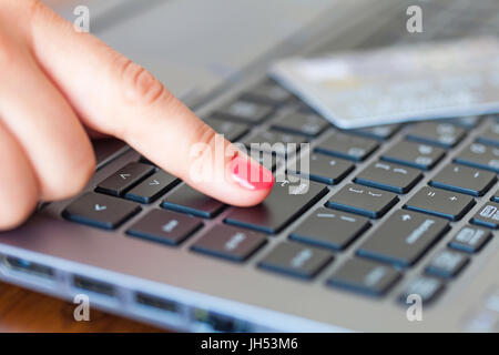Femmina lato premendo il tasto invio e la carta di credito in background, fondale campo di profondità Foto Stock