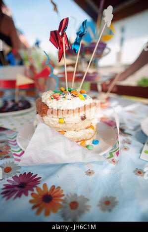 Bambini torta del close-up buon compleanno. In estate, su un picnic, all'aria aperta Foto Stock