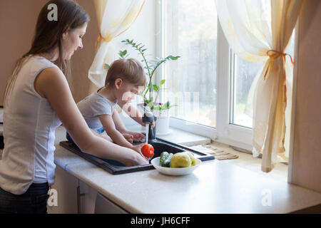 Cucina mamma figlio lavare frutta e verdura Foto Stock