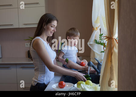 Cucina mamma figlio lavare frutta e verdura Foto Stock