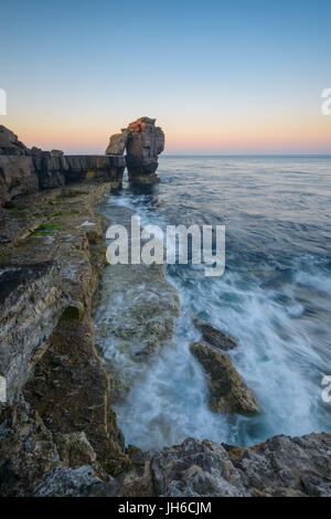 Twilight rompe su il celeberrimo pulpito Rock al Portland Bill su una chiara mattina di primavera lungo la Jurassic Coast in Dorset, England, Regno Unito Foto Stock