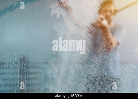 Uomo auto lavaggio in self-service car wash stazione, visto dall'interno del veicolo, il fuoco selettivo Foto Stock