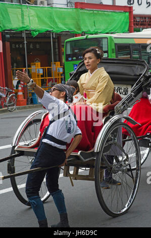 Tokyo rickshaw parlando con un cliente signora vestita in kimono Foto Stock