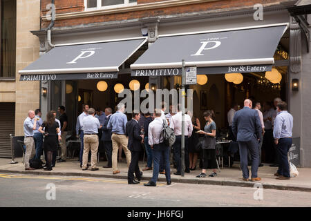 Persone in piedi a bere e mangiare su un marciapiede fuori da un primitivo ristorante nel centro della città di Birmingham, Regno Unito Foto Stock
