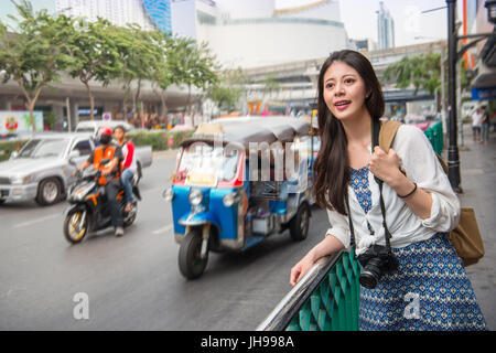 Donna in piedi turistiche nella trafficata strada di Bangkok con un bel sorriso raggiante su viaggi in Thailandia. Ragazza asiatica su strada durante le vacanze estive. Thai t.r.a. Foto Stock