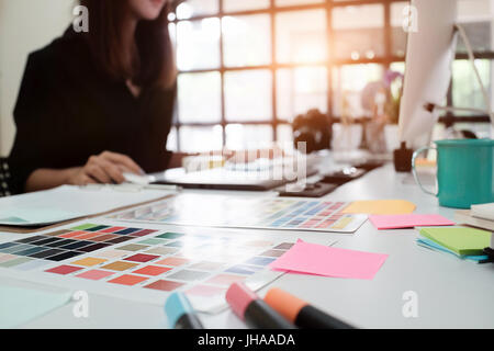 Il fuoco selettivo sulla tabella di creative e la donna graphic design la sfocatura sullo sfondo con tono vintage. Foto Stock