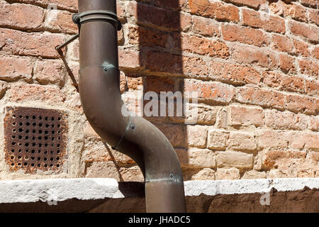 Vecchia grondaia pioggia su un muro di mattoni home Foto Stock