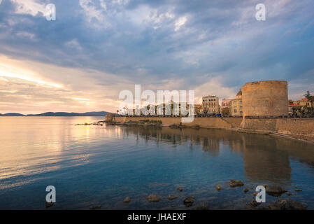 La costa della Sardegna, vista del seawall medievale e l'estremità meridionale della storica città vecchia al crepuscolo di Alghero, in Sardegna. Foto Stock
