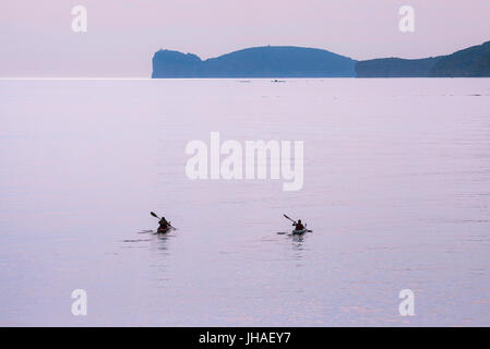 In kayak di mare, due kayakers impostato su off all'alba attraverso la baia ad Alghero Sardegna nord-occidentale. Foto Stock