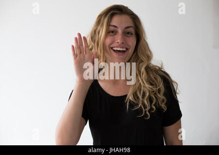 Giovani, Bionda, bella, milennial caucasica donna esprimere emozioni e felicità mentre agitando contro uno sfondo bianco. Invitante e accogliente. Foto Stock