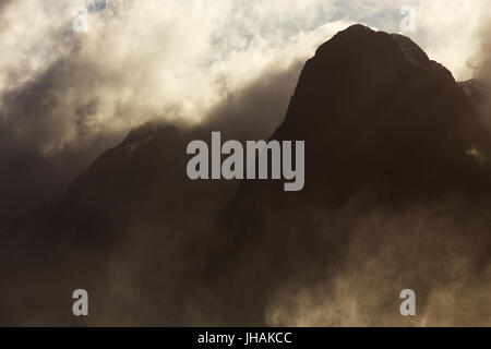 Infausto picchi di montagna avvolto nella nube illuminata e la nebbia. Foto Stock