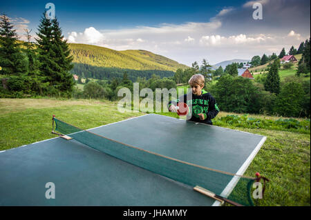 Scuola ragazzo giocando a ping-pong per esterno Foto Stock