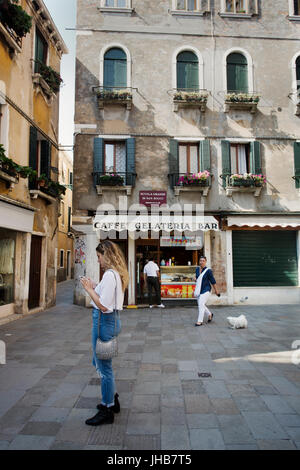 Un giovane, Bionda, bella milennial esplorare e vagare per le strade di Venezia, Italia e Europa in estate. Un famoso storico di destinazione di viaggio Foto Stock