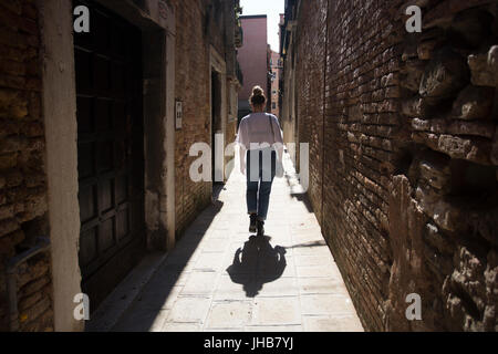 Un giovane, Bionda, bella milennial esplorare e vagare per le strade di Venezia, Italia e Europa in estate. Un famoso storico di destinazione di viaggio Foto Stock