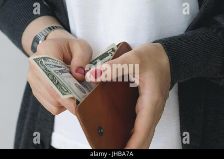 La ragazza paga nel negozio. Mani tenendo aperta la pelle sottile arancione portamonete con dollari in contanti. Foto Stock